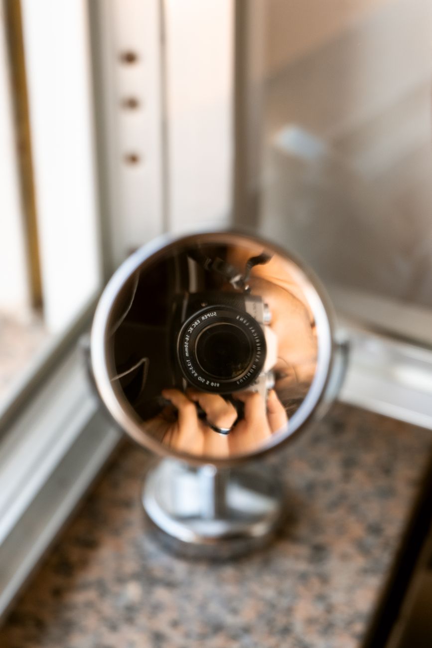 lens of a camera reflecting in a small round mirror